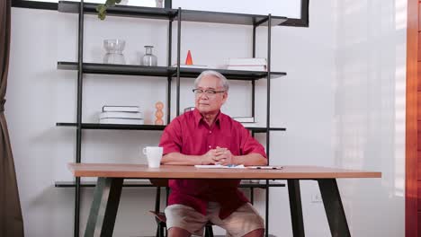 Hombre-Asiático-Mayor-Sentado-Sobre-El-Escritorio-De-La-Oficina-Relajante