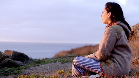 woman-watching-the-sunset-on-the-beach,-with-a-beautiful-warm-sunset-light,-calm-and-relaxed,-profile-shot,-coast-of-chile