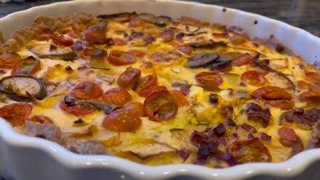 Close-up-pan-shot-of-fresh-Homemade-Quiche-Lorraine-With-tomatoes,-Mushrooms,bacon-And-Cheese
