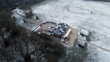 Large-house-Epping-forest-Essex-UK-snow-covered-frozen-field-and-gardens-aerial-POV