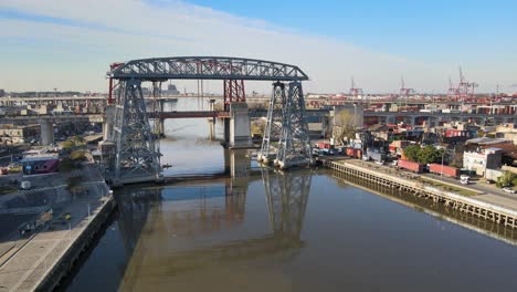 Aerial-pan-over-Riachuelo,-showing-historical-Transporter-Bridge,-Buenos-Aires