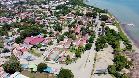 Aerial-drone-of-capital-city-Dili-in-Timor-Leste,-South-East-Asia,-static-of-remote-tropical-island-over-buildings,-traffic-and-ocean