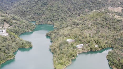 Ascending-tilting-camera-view-of-Spectacular-View-of-Feitsui-Reservoir,-Emerald-lake,-Thousand-Island-Lake-is-Second-largest-water-reservoir-dam-water-supply-in-Taiwan-leading-to-mountainous-view