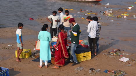 A-Local-customers-buying-fishes-from-a-fish-seller-women,-started-her-retail-fish-selling-near-a-beach-shore,-crowd-buying-fishes-near-a-beach-shore-video-background-in-Pro-res-422-HQ