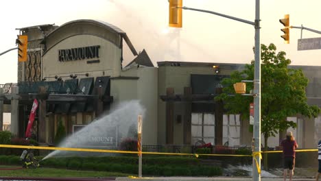 Man-Taking-Video-While-Firefighters-Extinguish-Fire-At-Paramount-Fine-Foods-Restaurant-In-Mississauga,-Canada-At-Daytime