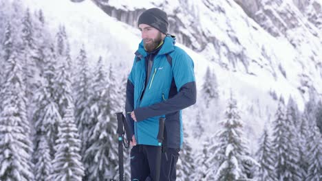 Bärtiger-Skifahrer-Schließt-Jacke-Im-Verschneiten-Waldberg