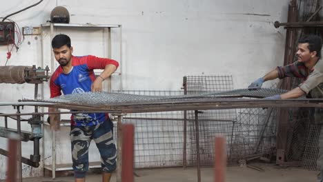 Factory-Worker-Using-Hammer-To-Release-Wire-Mesh-Reinforcement-From-Frame