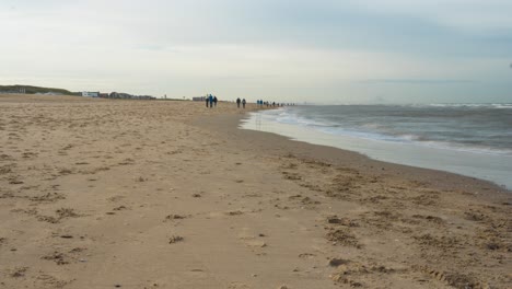 Gente-Caminando-En-La-Playa-En-Una-Mañana-Fría-En-Holanda