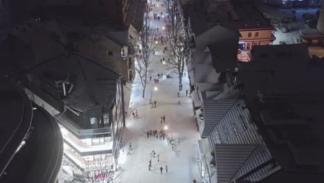 Aerial-view-over-main-street-of-Zakopane-in-Krupowki-neighborhood-at-night-with-people-walking