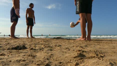 Real-suntanned-playful-boys-have-fun-enjoying-playing-football-on-sandy-beach-in-Italy