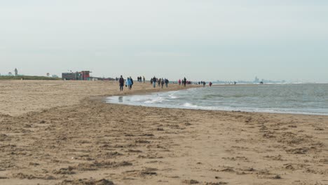 Timelapse-De-Personas-Caminando-Y-Montando-A-Caballo-En-La-Playa-De-Arena-En-Katwijk,-Zuid-Holland,-Países-Bajos