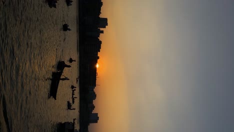 Silhouette-Of-Local-Boatmen-On-Buriganga-River-Against-Orange-Sunset-Skies