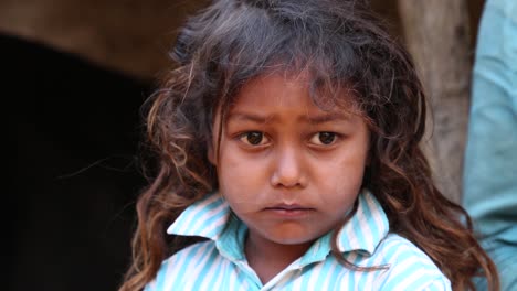 Handheld-portrait-of-unhappy-Indian-child-girl-from-rural-village-looking-at-camera,-India