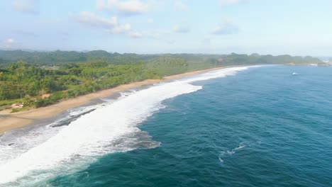 Calm-ocean-waves-wash-tropical-beach-on-Asmara-coast,-East-Java-Indonesia-aerial