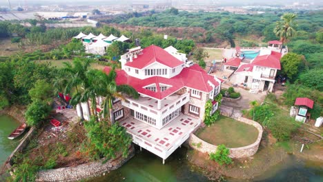 Cerca-Del-Techo-De-Tejas-Rojas-Y-La-Lujosa-Casa-De-Vacaciones-Blanca-Rodeada-De-Bosques-Y-Vegetación-Nativa-Con-Un-Hermoso-Lago-Y-Piscina-En-Vadodara,-India