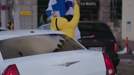 Person-Schwenkt-Eine-Flagge-Aus-Autofenstern-Und-Feiert-Die-Olympische-Eishockeymeisterschaft-In-Helsinki,-Finnland