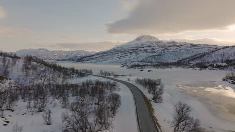 A-Lone-Car-Driving-Through-A-Snowy-Landscape-In-Skogsfjordvatnet,-A-Lake-On-Ringvassoya