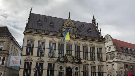 Ukrainian-Flag-flying-on-Haus-Schütting,-Bremen,-cloudy-day