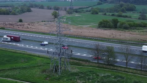 Speeding-traffic-passing-pylon-electricity-tower-on-M62-motorway-aerial-view-slow-right-orbit