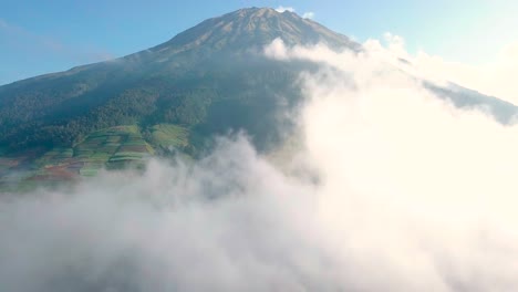 Aerial-flight-through-dense-white-clouds-and-beautiful-Mount-Sumbing-in-background-during-sunny-day