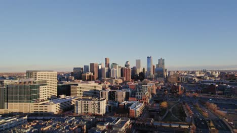 Drohnen-Luftaufnahme-Der-Skyline-Von-Denver,-Colorado,-Die-Zurückfliegt,-Vorbei-Am-Zusammenfluss-Eines-Modernen-Apartmentkomplex-Hochhauses-Während-Des-Sonnenuntergangs-Zur-Goldenen-Stunde
