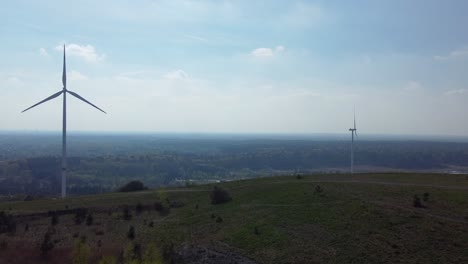 Huge-wind-turbines-behind-old-mining-heap-in-Belgium,-aerial-ascend-view