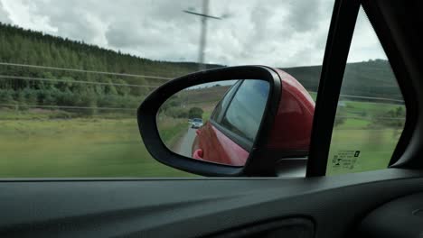 El-Coche-Plateado-Persiguiendo-A-Un-Coche-Rojo-Visto-En-Un-Espejo-Retrovisor-Con-Un-Fuerte-Efecto-De-Desenfoque-De-Movimiento