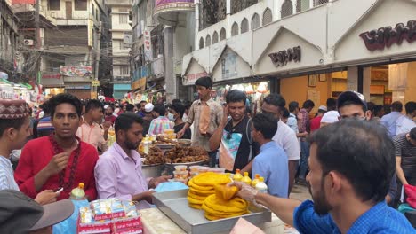 Close-up-shot-of-local-fast-food-sellers-selling-fast-foods-in-an-old-traditional-biggest-Iftar-street-food-market-in-Dhaka,-Bangladesh-surrounded-by-buildings