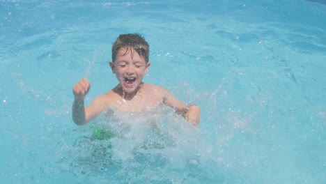 Aktiver-Junge-Tobt-Im-Pool,-Winkt-Mit-Den-Armen-Und-Spritzt-Auf-Die-Wasseroberfläche,-Sommerurlaub