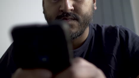 Low-Angle-View-Of-Lower-Half-Of-Bearded-Indian-Male-Holding-Smartphone-And-Typing