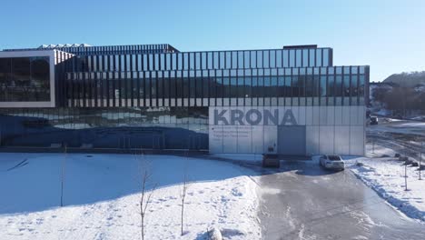 Beautiful-Krona-building-in-Kongsberg-Norway---Sunny-winter-day-ascending-and-rotating-aerial-showing-building-exterior-and-logo