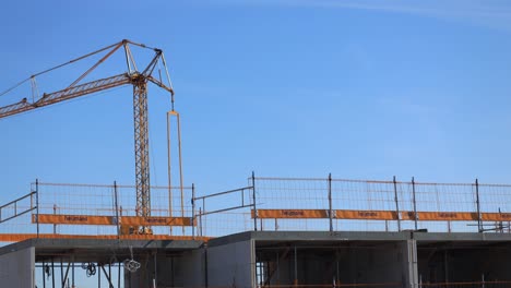 Time-lapse-showing-construction-work-with-small-crane-adding-floor-material-on-top-of-building-with-large-yellow-crane-behind