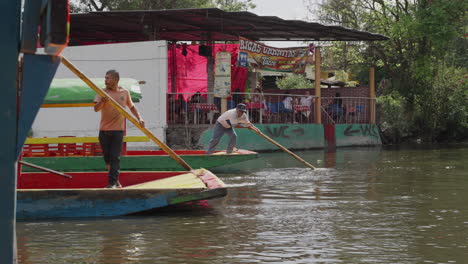 Pair-Of-Gondoliers-Using-Long-Wooden-Rowing-Oar-To-Push-Gondola-Along-The-Xochimilco-Canals