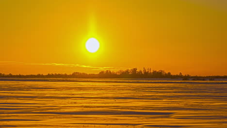 Time-lapse-shot-of-golden-sunset-at-sky-lighting-outdoors-on-snowy-winter-field