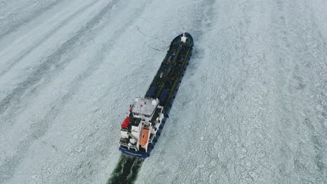 Aerial-top-down-panning-view-of-oil-and-chemical-tanker-CRYSTALWATER-call-sign-ESLI,-moving-ahead-in-ice-covered-Finnish-archipelago