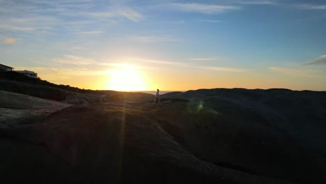 Silhouette-Eines-Jungen-Mädchens,-Das-Bei-Sonnenuntergang-Auf-Großen-Felsbrocken-Am-Strand-Von-Llandudno-In-Kapstadt-Läuft