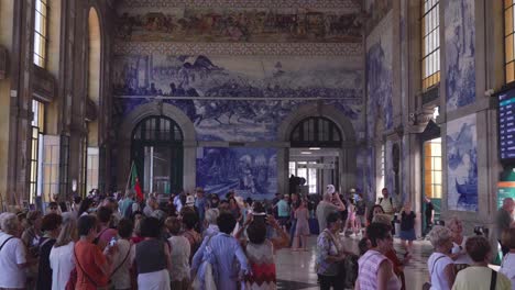 Interior-De-Personas-En-El-Hall-De-Entrada-De-La-Estación-De-Tren-De-Sao-Bento,-Hito-Arquitectónico-En-El-Centro-Histórico-De-Oporto,-Portugal,-Mural-De-Azulejos-Azules-En-La-Pared-2022