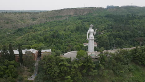 Arc-aerial-shot-of-the-Kartlis-Deda-statue-and-a-beautiful-Tbilisi-landscape