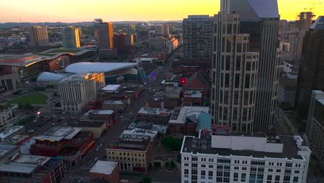 Aerial-view-around-the-AT-T-building-revealing-the-Broadway-street,-sunset-in-Nashville,-USA---circling,-drone-shot