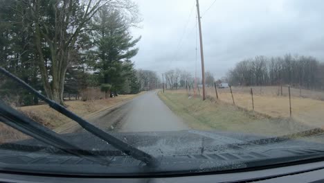 POV-thru-the-windshield-and-active-windshield-wipers-during-a-light-rain-while-driving-on-a-county-road-in-rural-Illinois-in-early-spring
