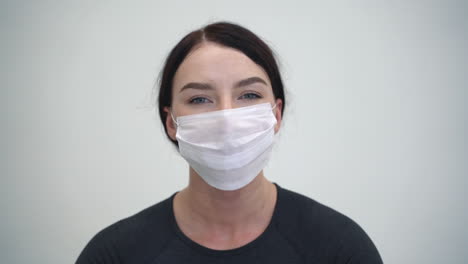 Portrait-of-woman-putting-on-medical-face-mask-before-practicing-yoga-and-workout-at-home