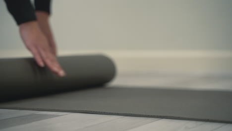 Young-woman-unrolls-yoga-mat-on-floor-and-prepares-to-meditate-and-do-exercises.-Close-up.