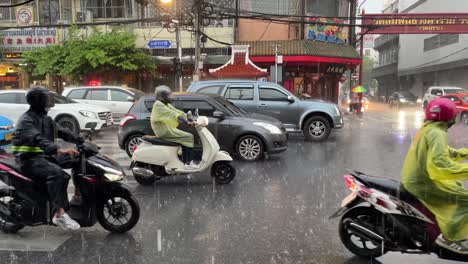 Cars-and-motorbikes-waiting-at-traffic-function-at-Chinatown-on-a-rainy-day,-Bangkok,-Thailand