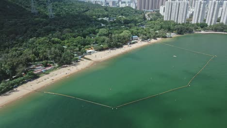 Cinematic-view-of-the-beach-near-Tuen-Mun,-Hong-Kong-which-is-surrounded-by-a-green-hill