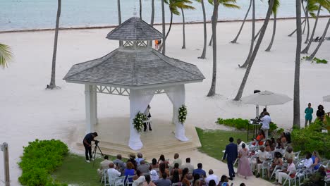 La-Madre-De-La-Novia-Camina-Por-El-Pasillo-De-La-Boda-Con-Los-Invitados-En-La-Boda-Al-Aire-Libre-En-Un-Resort-Tropical