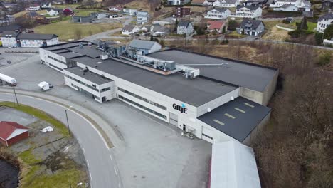 Acercándose-A-Las-Instalaciones-De-Producción-De-Gilje-En-Moi-Noruega---Exterior-De-La-Fábrica-De-Puertas-Y-Ventanas---Edificio-De-Aproximación-Aérea-Con-Logotipo