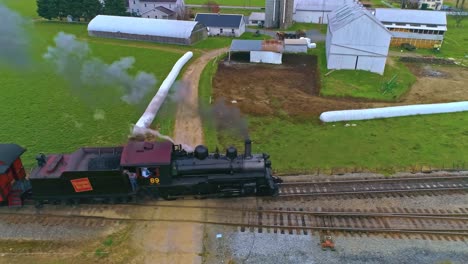 An-Aerial-View-of-an-Antique-Restored-Steam-Train-and-Passenger-Coaches-Approaching-With-Smoke-and-Steam-Pulling-into-the-Yard-and-Station-as-Seen-by-a-Drone