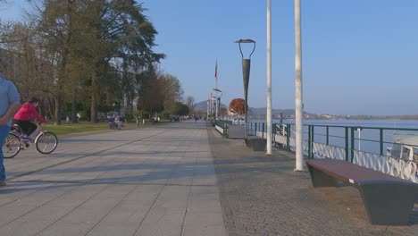 First-person-view-from-bicycle-of-people-and-bikers-at-Arona-lakeside-promenade