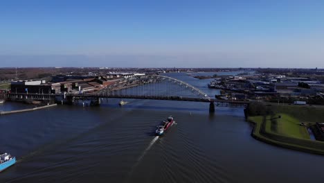 Luftaufnahme-Der-Bogenbrücke-Mit-Einem-Lastkahn,-Der-Am-Fluss-Noord-Unter-Strahlend-Blauem-Himmel-In-Südholland,-Niederlande,-Segelt