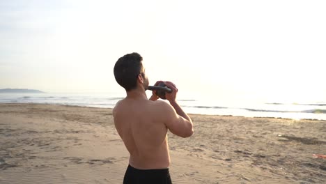 athlete-training-on-the-beach-with-kettlebell-against-backlight